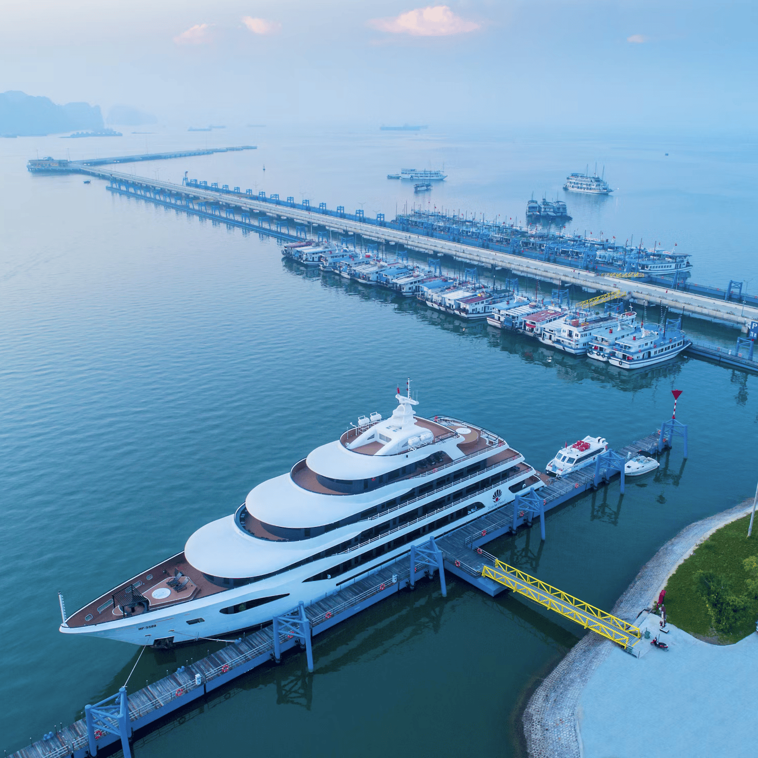 Large yacht docked at a pier with a scenic background